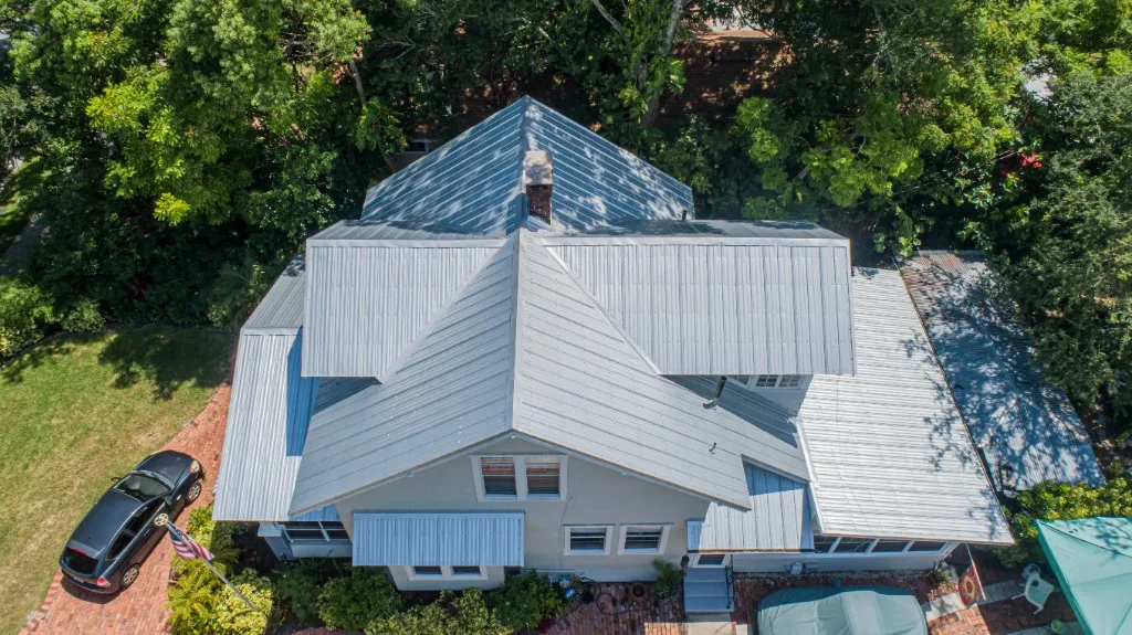 Aerial view of a completed Stronghold Roofing galvalume standing-seam metal roof over a historic Florida cottage with a brick driveway
