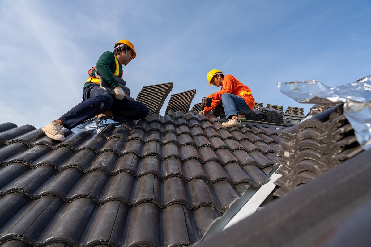Roofers checking tile roofs for patching