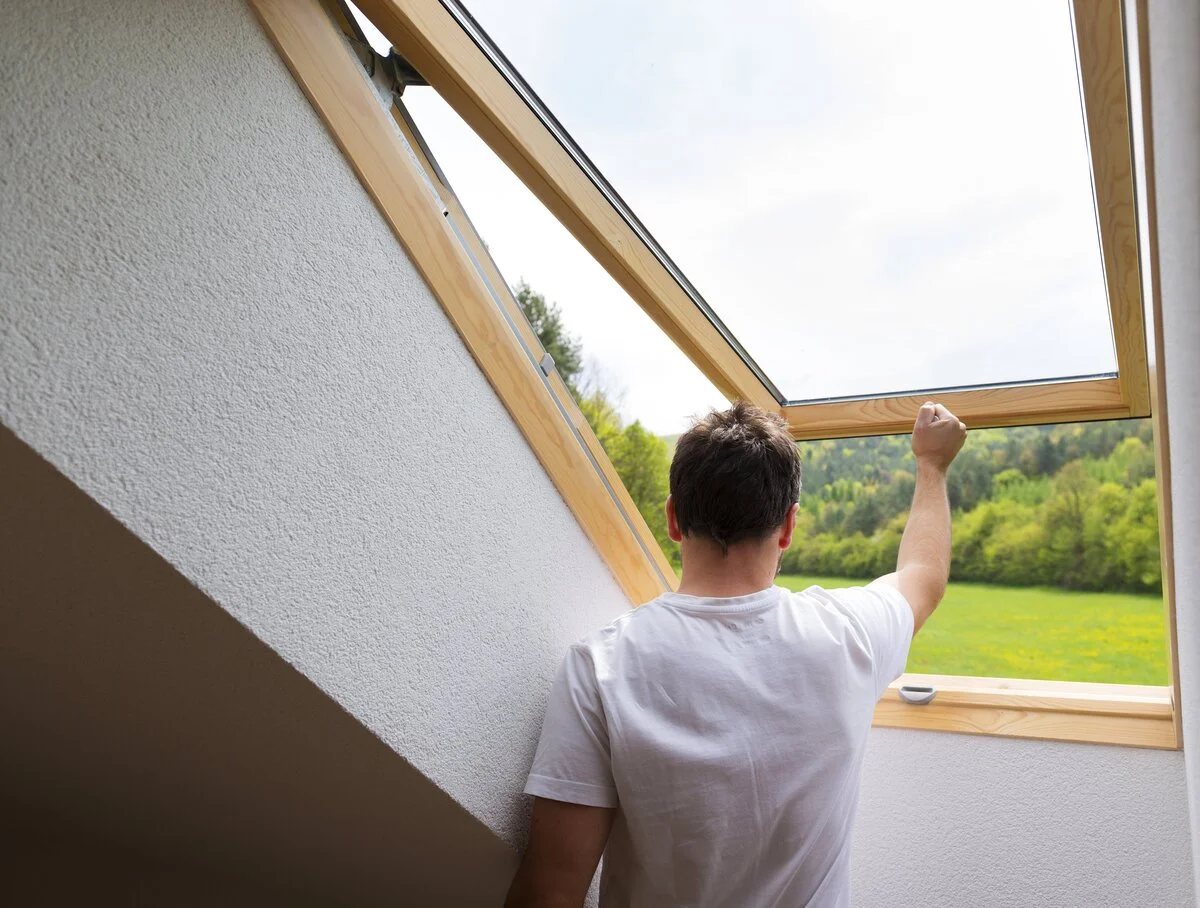 A man looking out of a skylight window