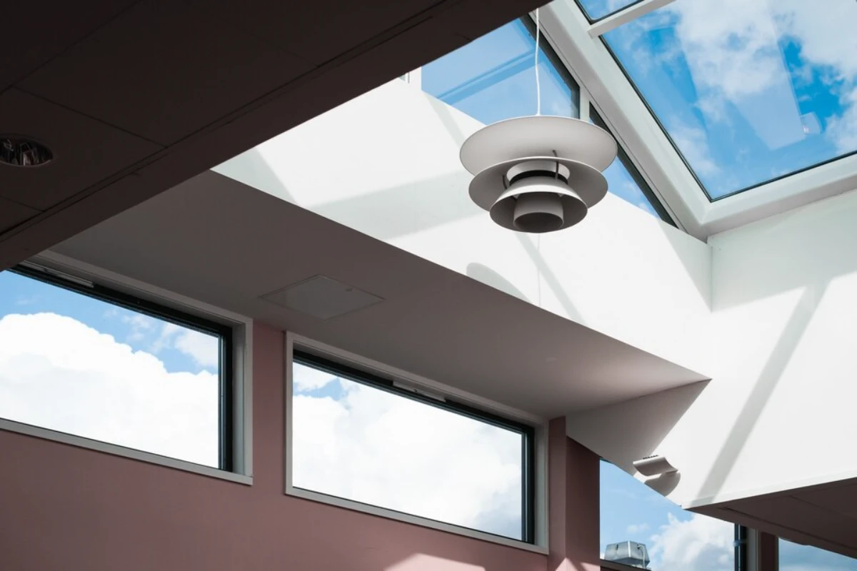 low angle shot of a lamp hanging inside a building with a roof skylight
