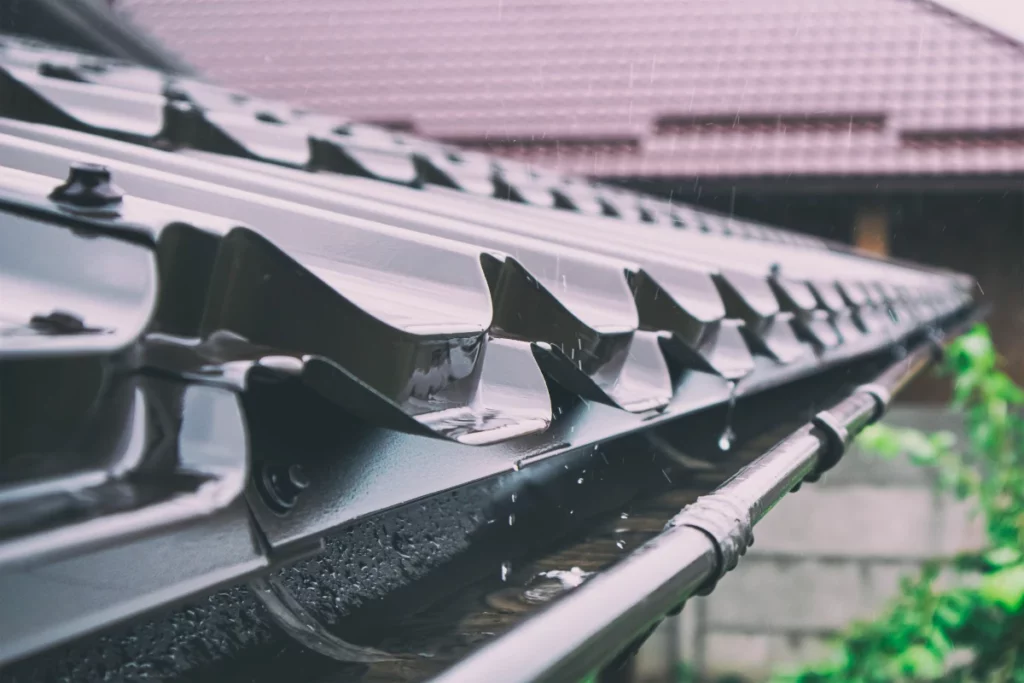 A close-up of rain falling on a gutter of Exposed Fastener Metal Roofing, capturing the raindrops.