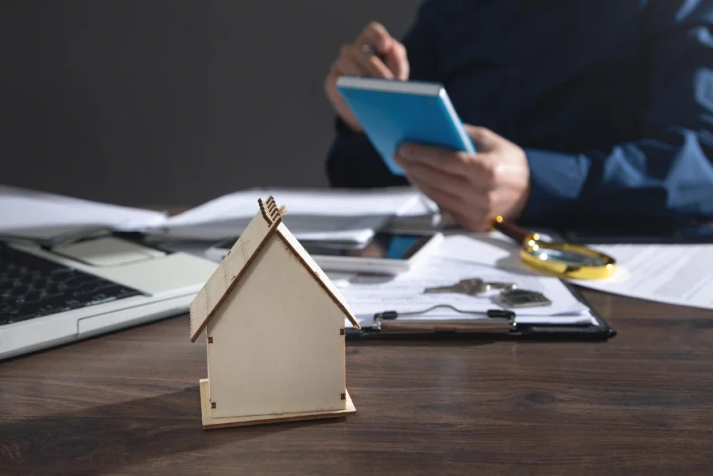 House model on the desk. Real estate agent working at office