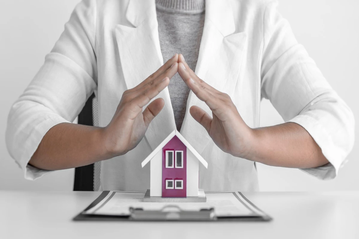 White-coated woman displays house model, representing Roof Warranty Transfer.