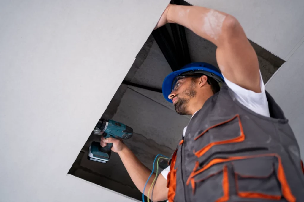 Worker in safety gear conducting Skylight Maintenance on a ceiling.