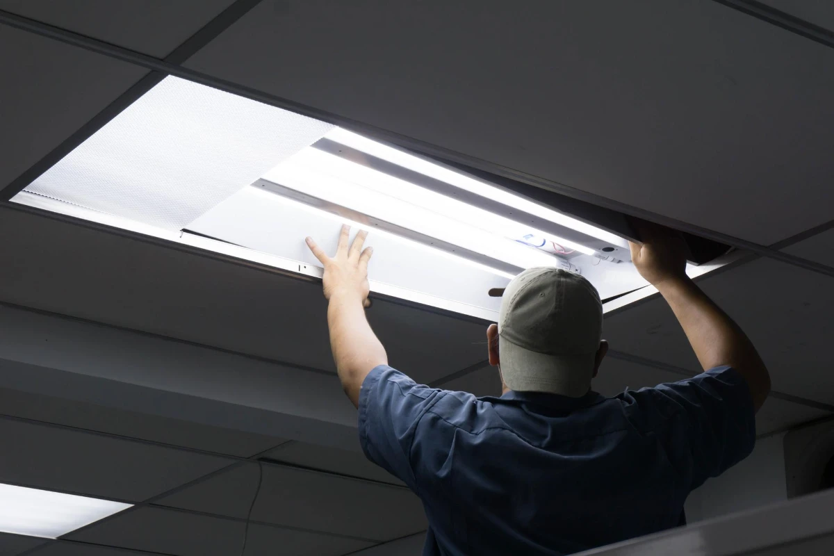 Man installing light fixture in ceiling, replacing skylight.