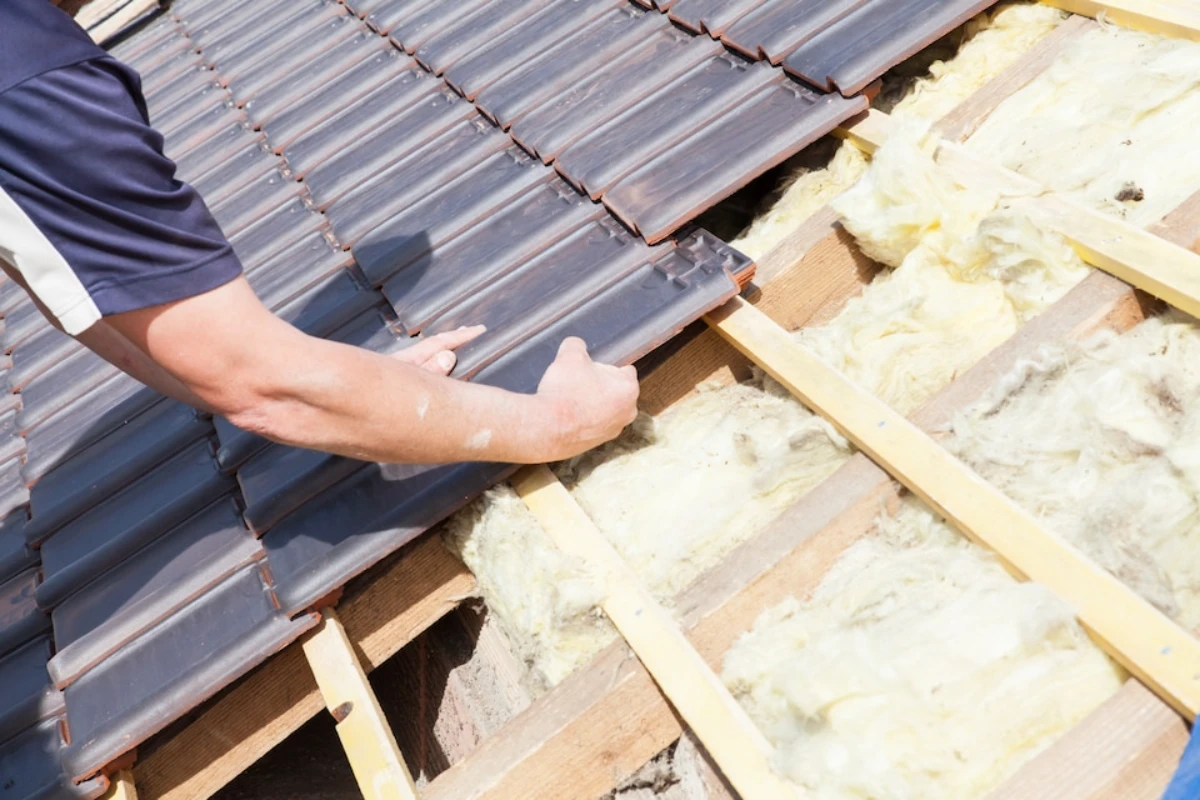 A man installs insulation on a roof, ensuring proper coverage for energy efficiency in residential construction.