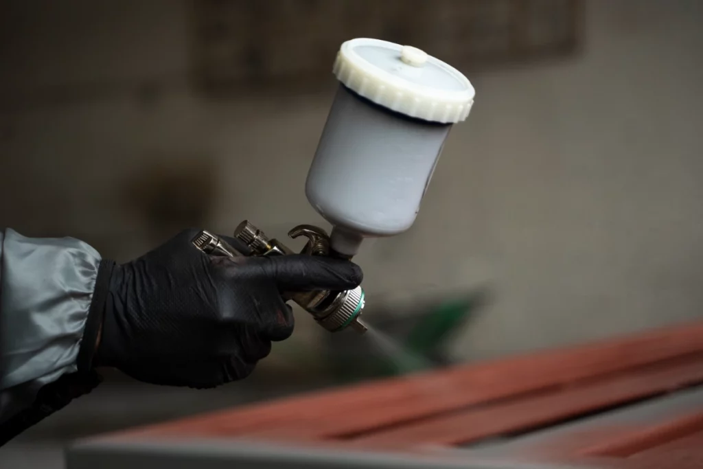 Side view hand spraying powder paint from a gun