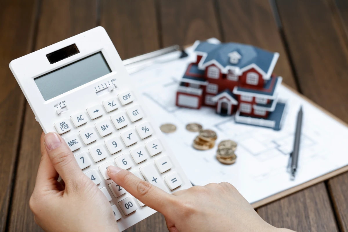 female hand operating calculator front villa house model