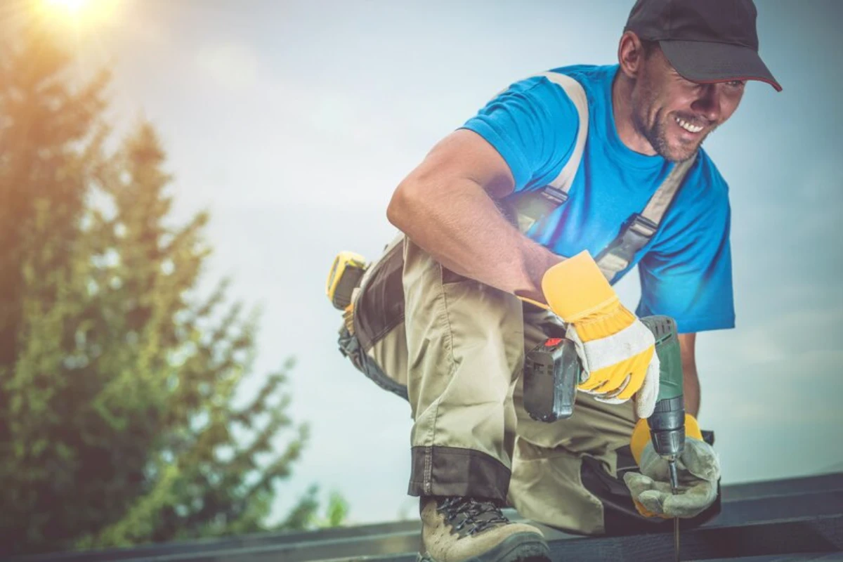 Low angle view of mid adult man kneeling on roof against sky