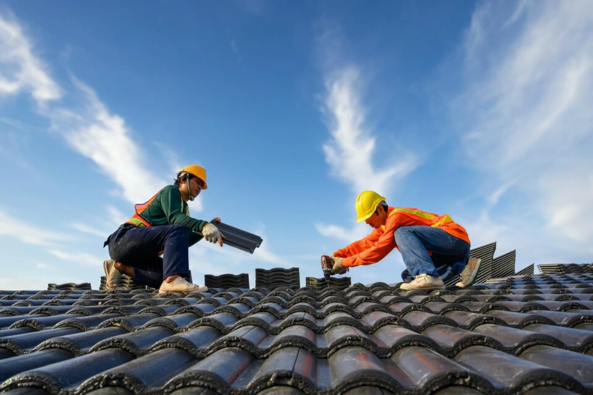Asian male roof installer Asian construction workers on the roof Work using a drill bit to fix ceramic or cement roofing screws on the construction site
