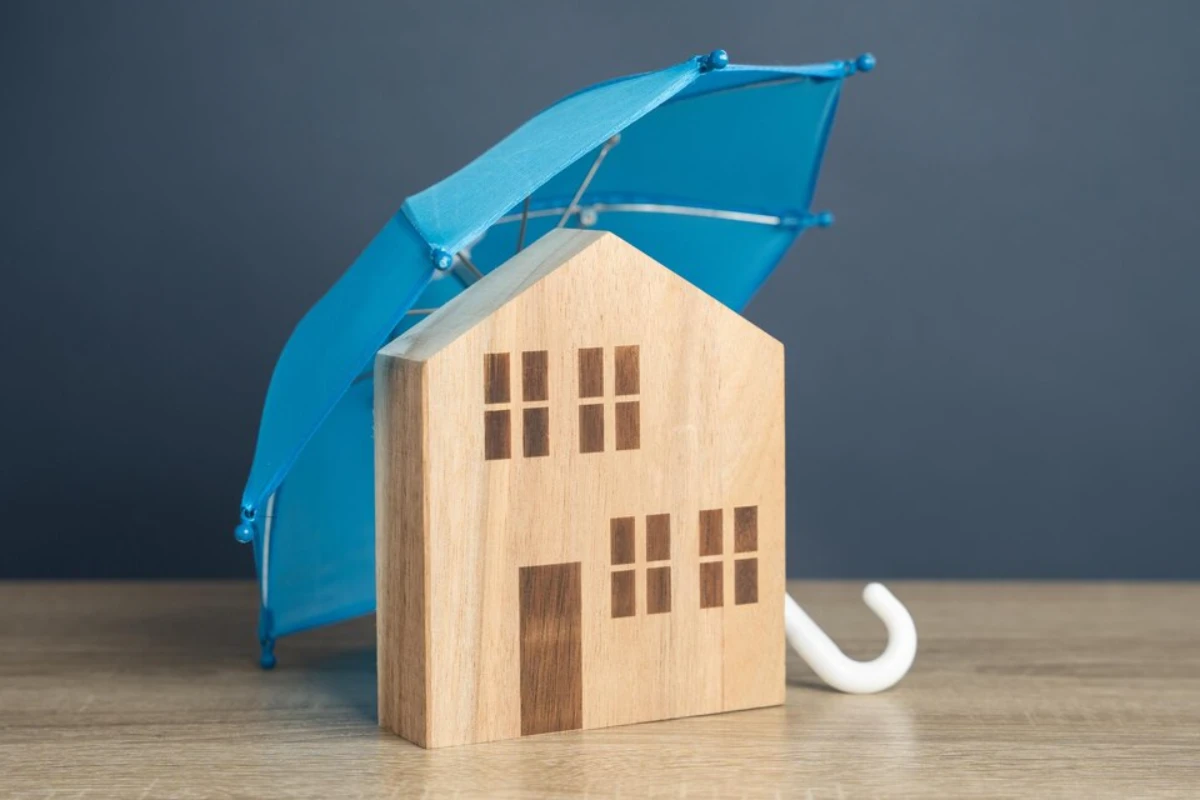 House with blue umbrella Property insurance Financial security Protect investment and be prepared for unforeseen events Repairs or rebuilding in the event of a covered loss 